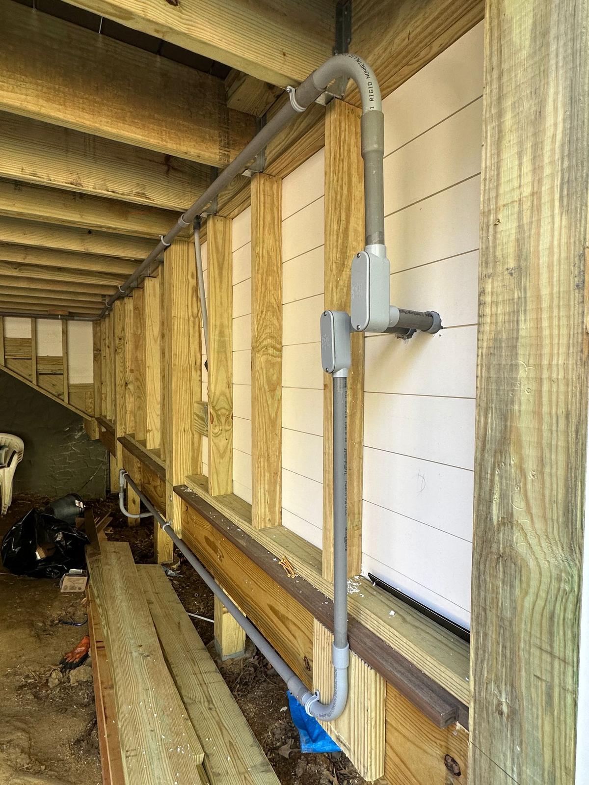 Rigid conduit run for exterior electrical feed under deck